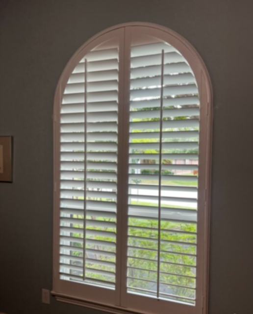Arched plantation shutters on a bedroom window